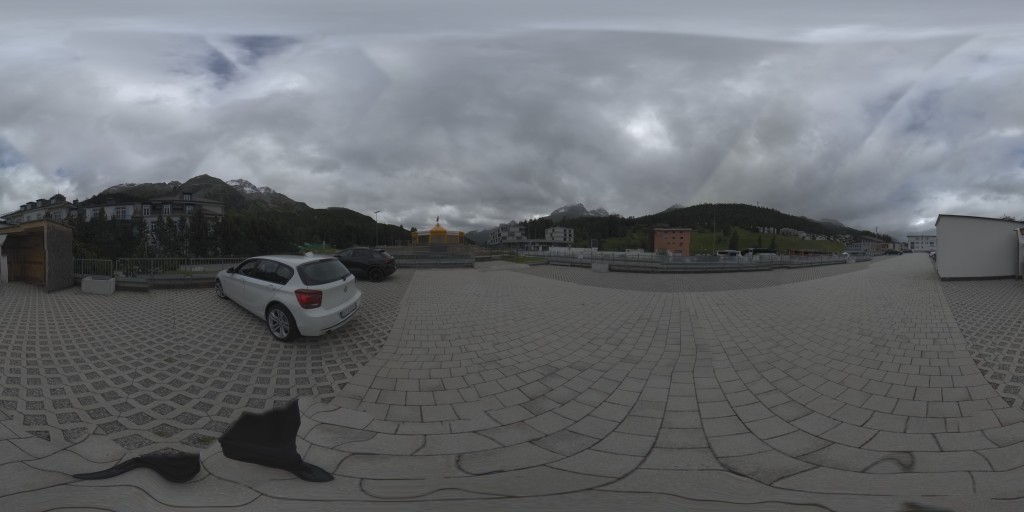360° HDRI of an alpine plaza with mountains and a dramatic cloudy sky